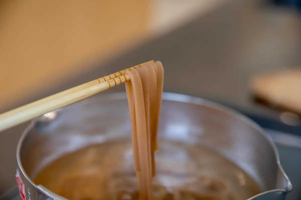Brown-rice noodles being checked during cooking